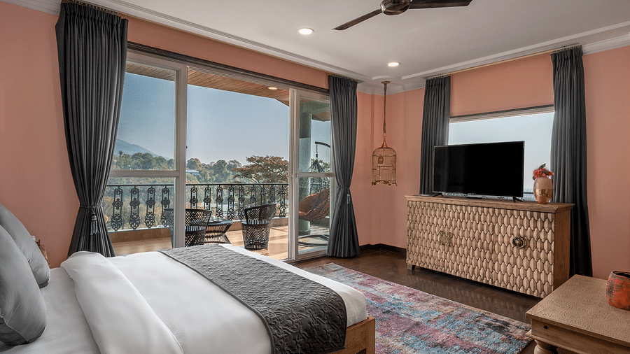 a bedroom with large windows leading out into the balcony and a large bed facing a television - Atman, Dharamshala