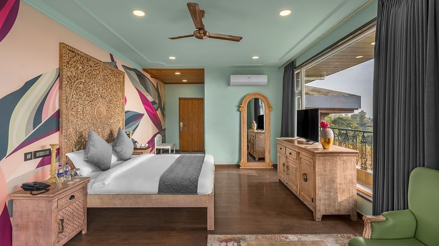 An image featuring a  bedroom with a comfortable bed, and a balcony. wooden flooring, wooden storage units - Atman, dharamshala