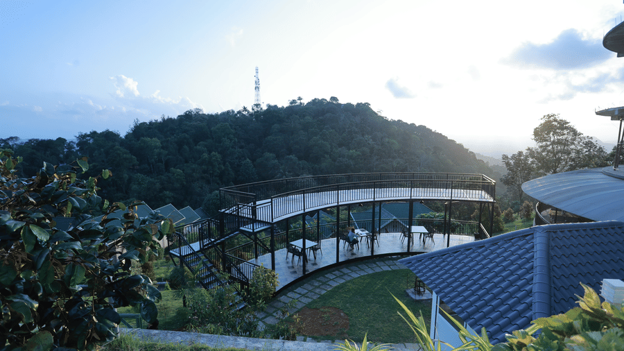 A curvy outdoor dining area overlooking the mountain valley and surrounded by the gardens at Aveda Mountains and Mist Resort and Spa, Munnar.