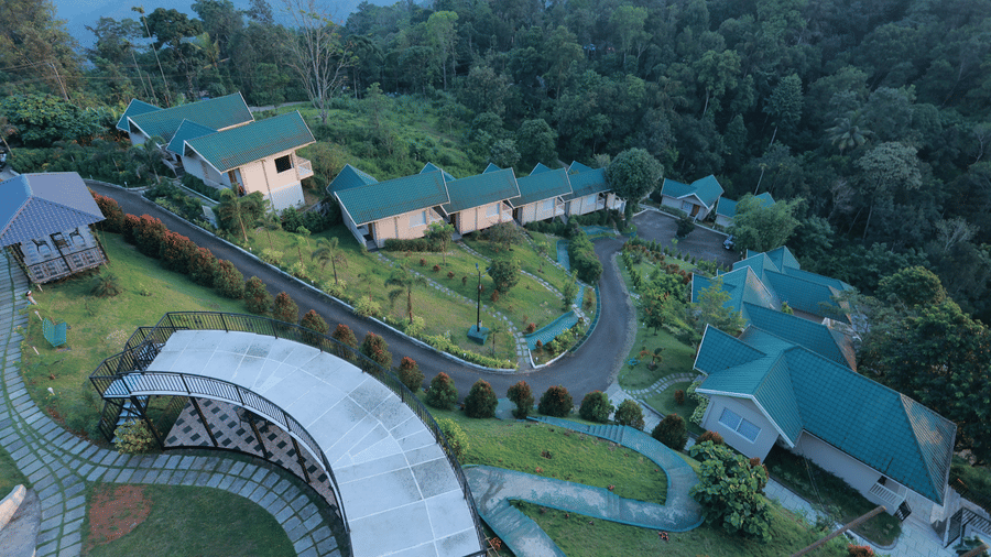 An aerial view of Aveda Mountains and Mist Resort and Spa, Munnar, with paved pathways through green garden patches leading to the villas.