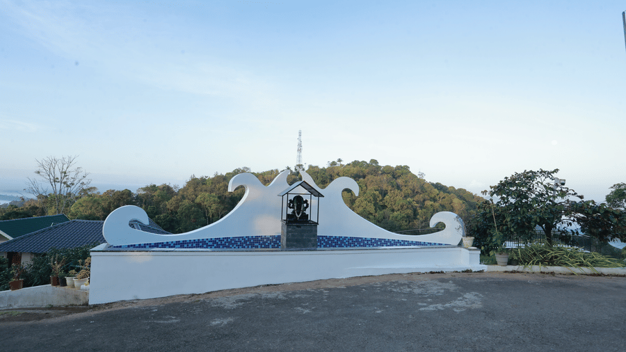 A white-coloured pedestal housing a black stone idol of Lord Ganesha right in front of the driveway of Aveda Mountains and Mist Resort and Spa, Munnar.
