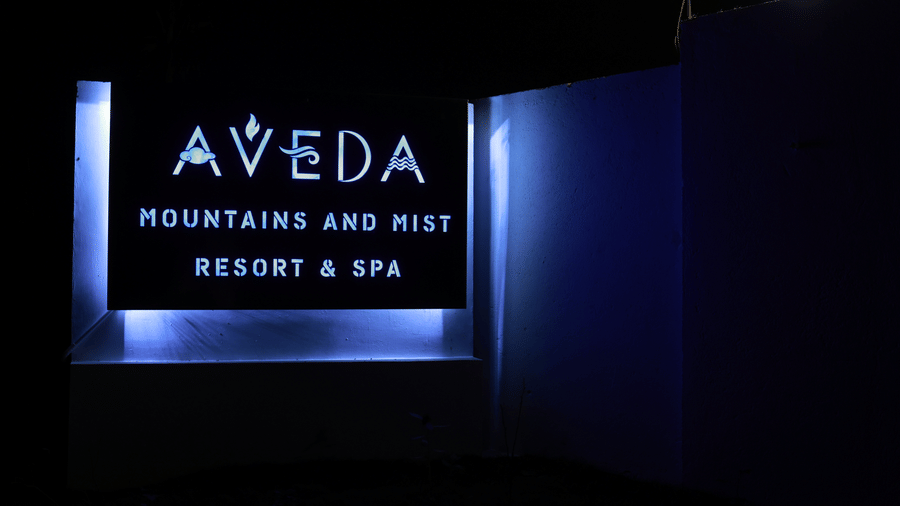 A back-lit sign board reading Aveda Mountains and Mist Resort and Spa, Munnar.