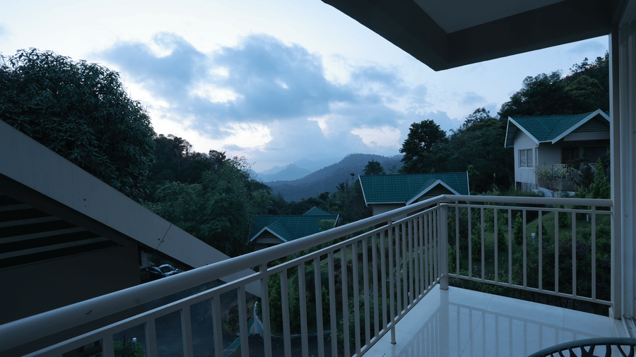 Beautiful valley views with lush greenery from the balcony at Aveda Mountains and Mist Resort and Spa, Munnar, overlooking a cloudy late-evening sky.