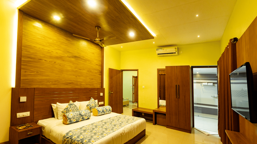 Full view of the Luxe Mountain View 2-Bedroom Family Villa featuring a double bed in a warmly lit interiors at Aveda Mountains and Mist Resort and Spa, Munnar.