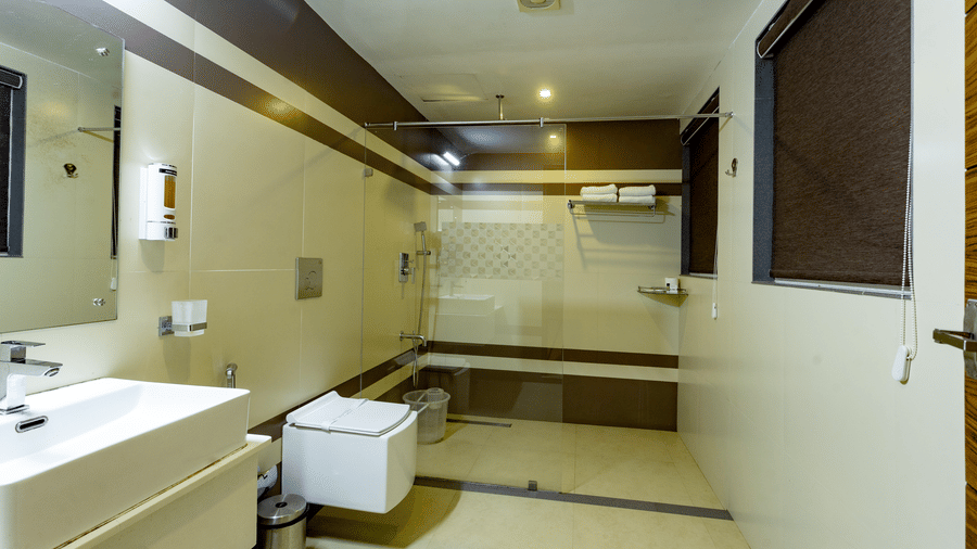 A spacious bathroom at Luxe Mountain View 2-Bedroom Family Villa with a wash basin, a commode, and a shower area at Aveda Mountains and Mist Resort and Spa, Munnar.