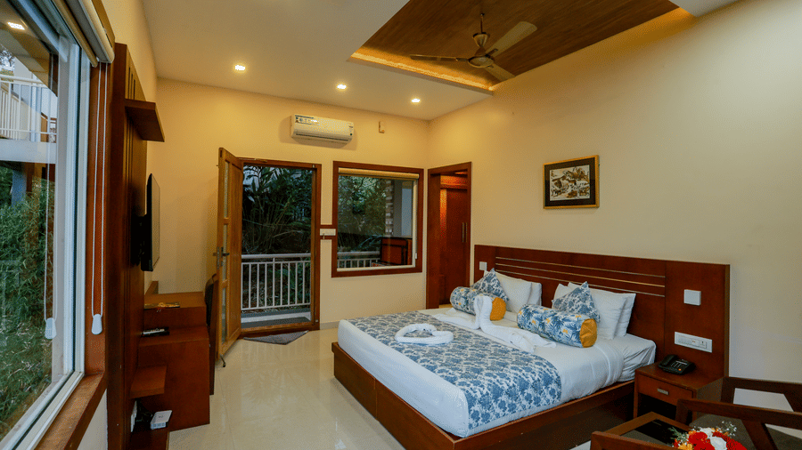 Full view of the Luxe Mountain View Cottage at Aveda Mountains and Mist Resort and Spa, Munnar, showcasing a double bed with patterned bed runner spread over it.