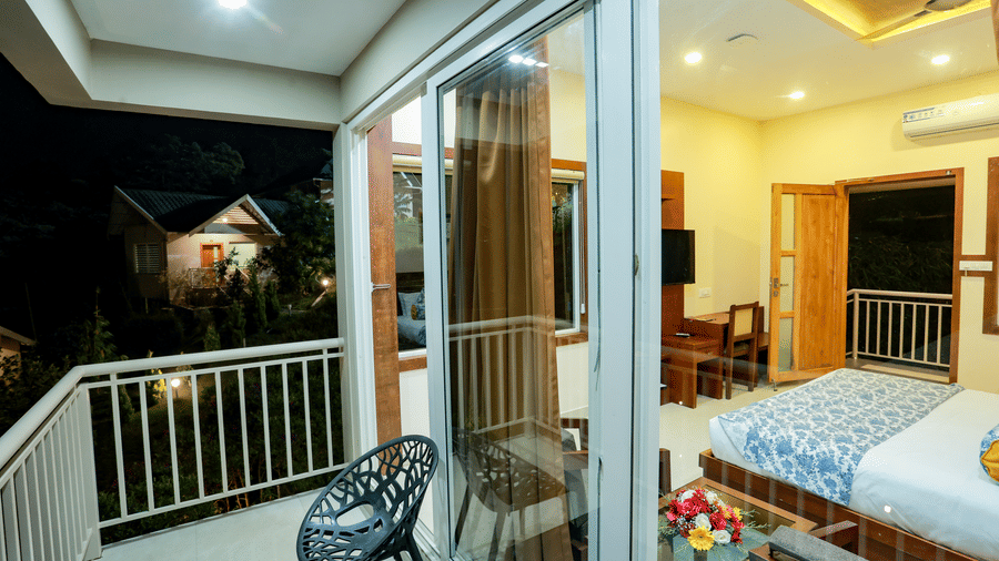 A panoramic shot of the Luxe Moutain View Cottage from the balcony during the night overlooking the brightly lit interiors at Aveda Mountains and Mist Resort and Spa, Munnar.