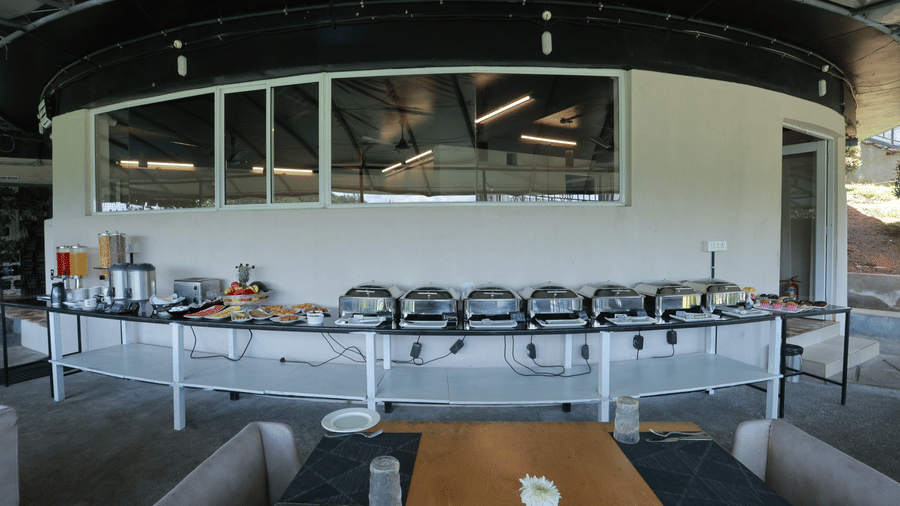 A wide-angle shot of the buffet table with chafing disheskept in a single line at the Machaan restaurant at Aveda Mountains and Mist Resort and Spa, Munnar.
