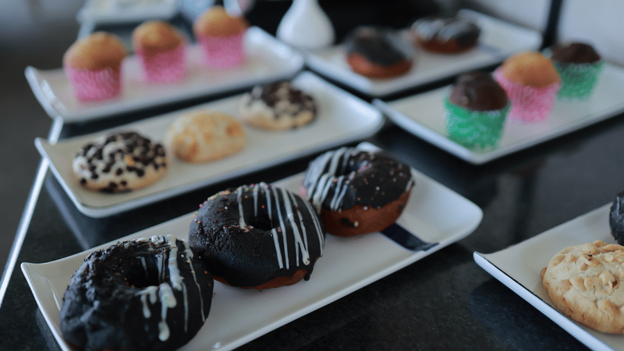 Close up of plates serving chocolate galzed donuts, cookies, cupcakes, and eclair at the Machaan restaurant at Aveda Mountains and Mist Resort and Spa, Munnar.