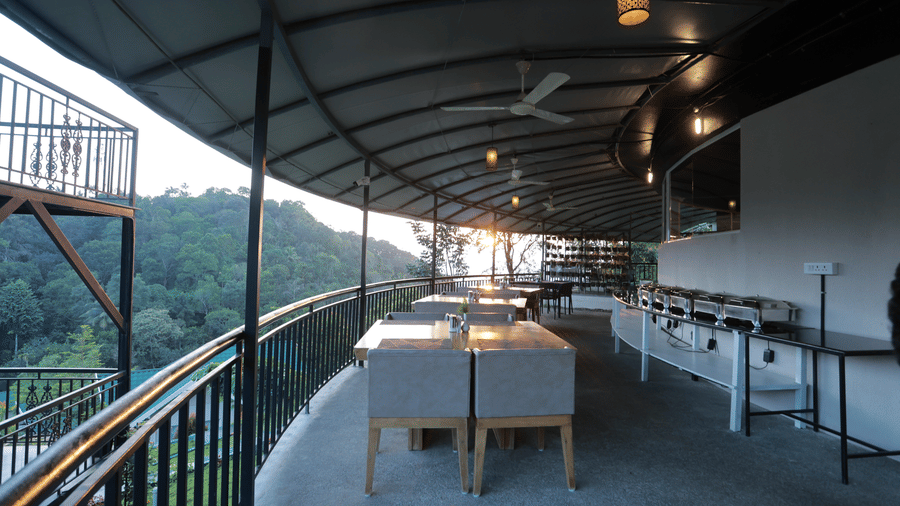 The dining area at the Machaan restaurant with well-arranged dining tables with the morning sun in the background at Aveda Mountains and Mist Resort and Spa, Munnar.