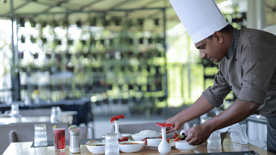 Chef wearing a white tall hat arranging dishes on a dining table at Grand Resort.