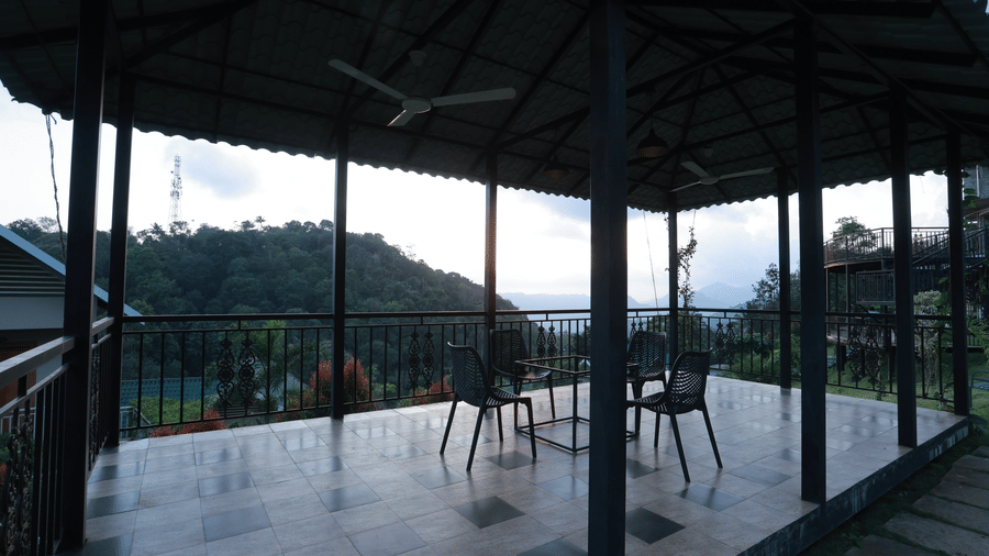 The outdoor dining area at the Machaan restaurant with tiled flooring, overlooking the lush green mountain views at Aveda Mountains and Mist Resort and Spa, Munnar.
