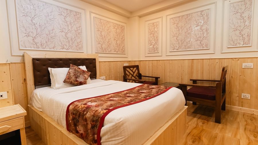An image of a bedroom with a king size bed and two chair next to it at Avianna New Mandala Hotel & Spa, Darjeeling.