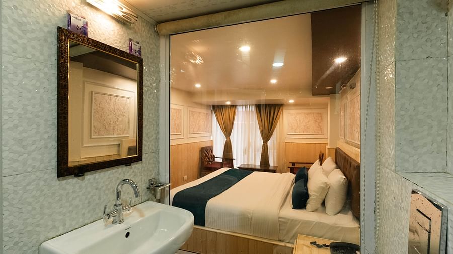 an image of a bedroom reflected through a bathroom mirror showcasing a bed with soft lighting at Avianna New Mandala Hotel & Spa, Darjeeling.
