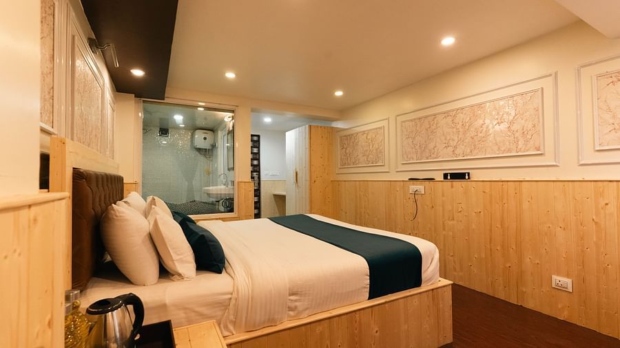 an image of a bedroom with a tea and coffee maker at an image of a bedroom reflected through a bathroom mirror showcasing a bed with soft lighting at Avianna New Mandala Hotel & Spa, Darjeeling.