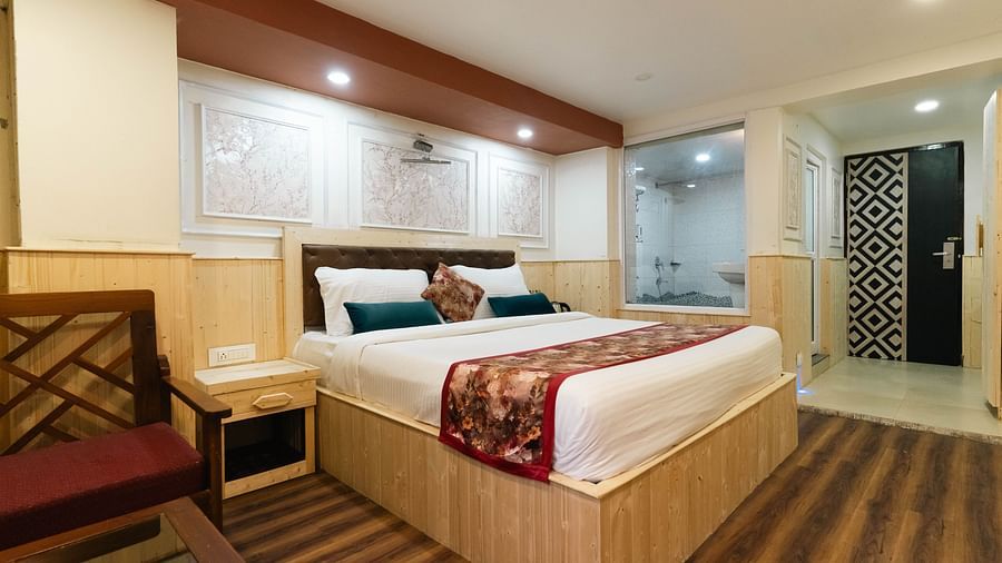an image of a bedroom with seating arrangements inside at an image of a bedroom with wooden strips flooring at Avianna New Mandala Hotel & Spa, Darjeeling.
