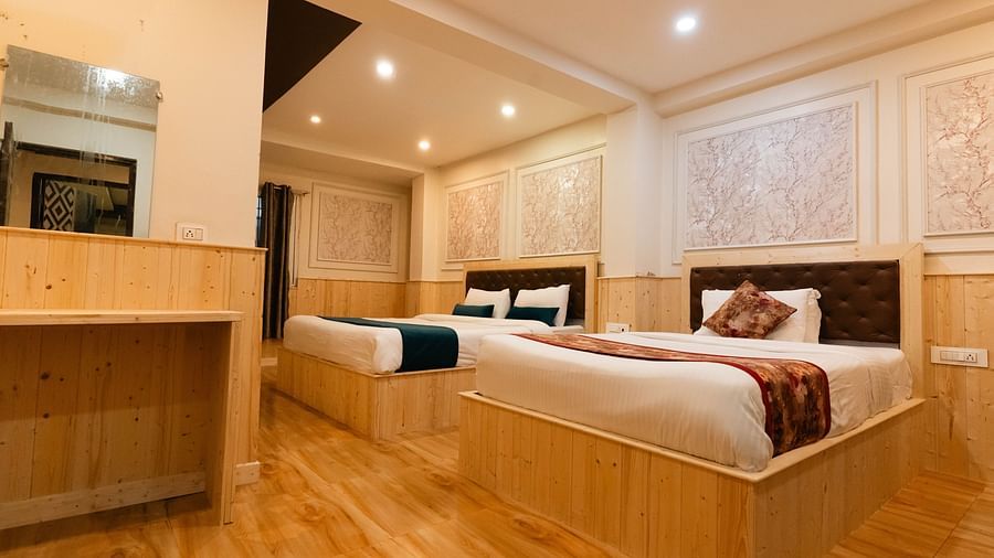 an image of a bedroom with one king size bed and one single bed placed closely at an image of a bedroom with wooden strips flooring at Avianna New Mandala Hotel & Spa, Darjeeling