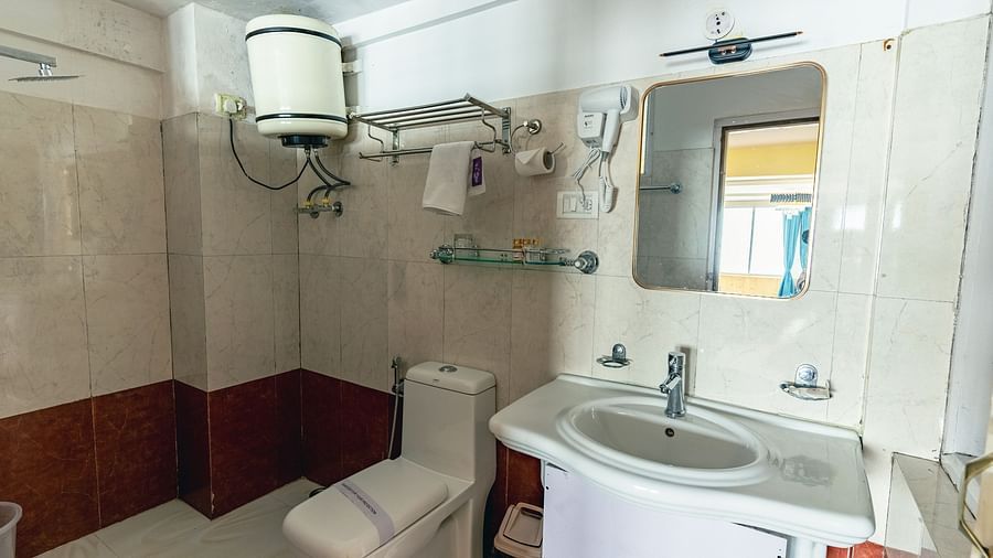 Deluxe rooms bathroom equipped with a washbasin, mirror, geyser, and western toilet3