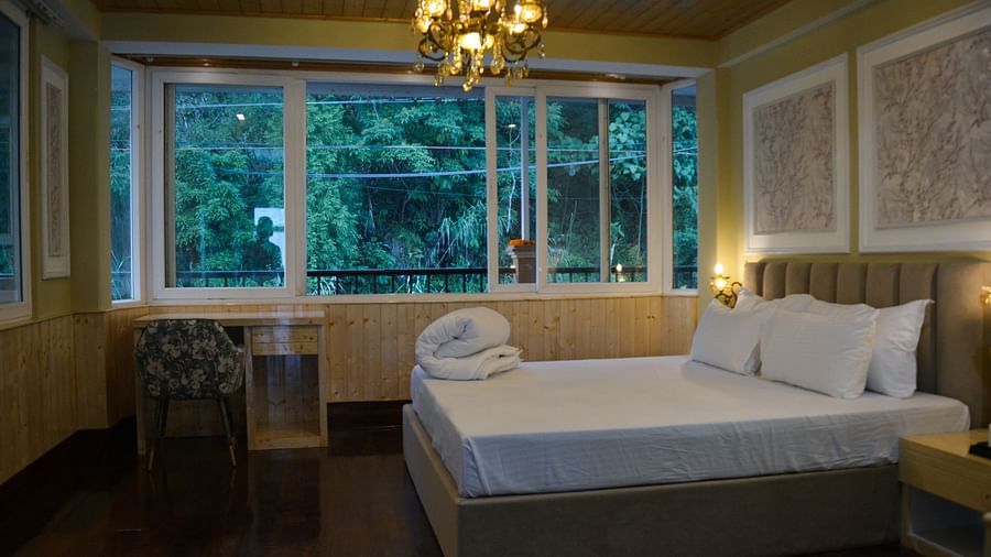 An image of a bedroom with king size bed with a side table with a chandelier and expansive window  - Avianna Windy House Wellness Retreat & Spa