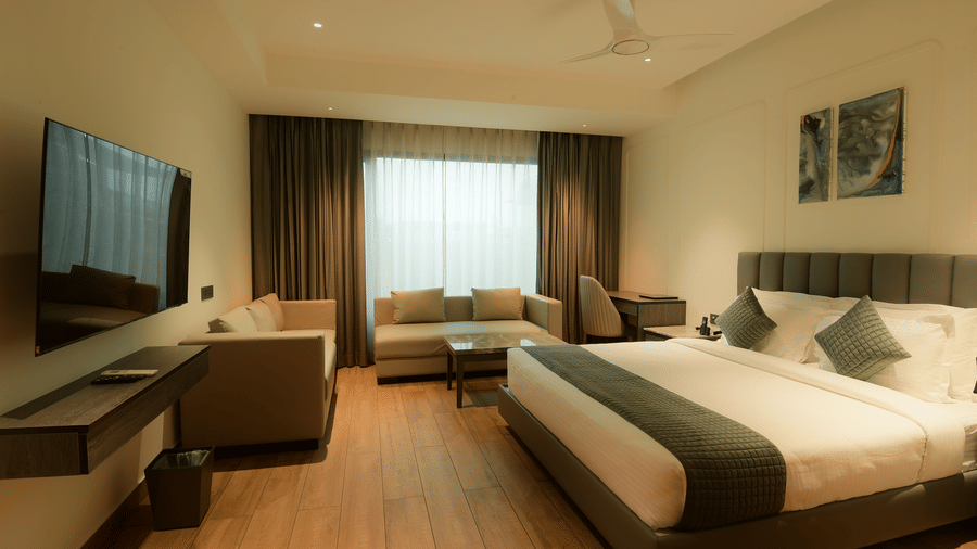 A bedroom featuring a king size bed, a television, and a seating area with a sofa at Awesome Palace, Guwahati Airport.