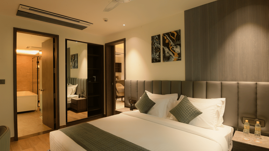 A bedroom featuring a king size bed, paintings, and an attached bathroom entrance at Awesome Palace, Guwahati Airport.
