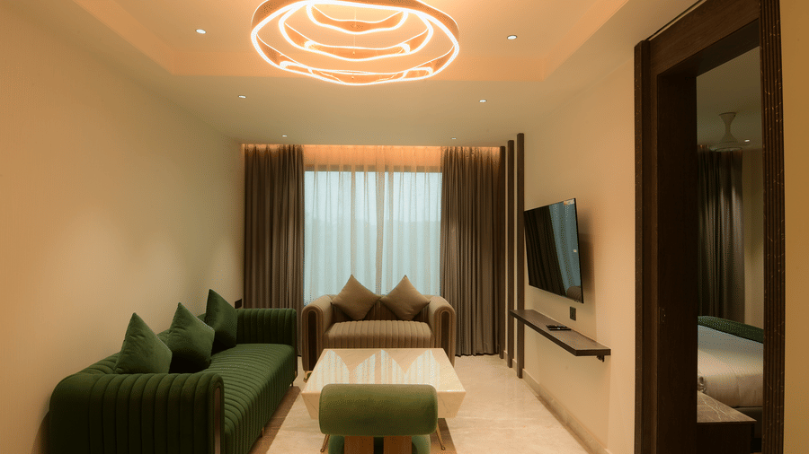 A living area featuring a sofa set, a coffee table, and a television at Awesome Palace, Guwahati Airport.