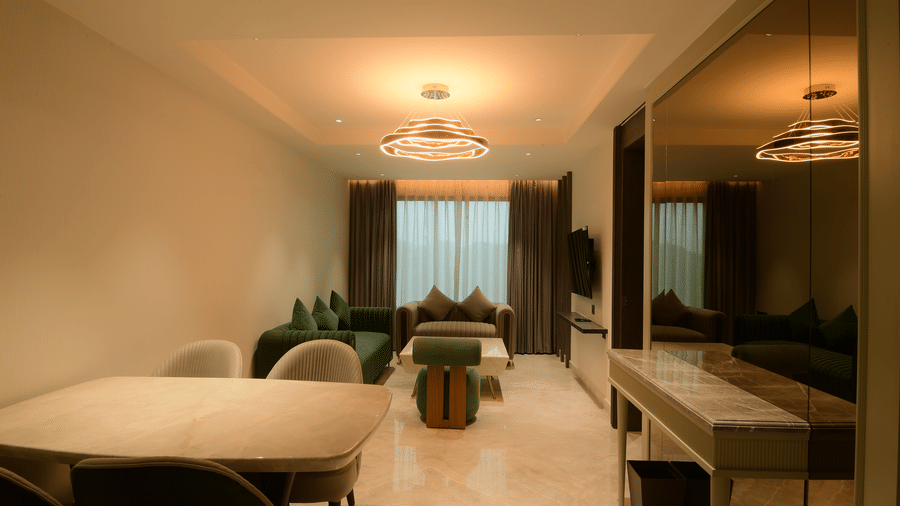 A spacious suite showcasing a dining table with chairs, a living area, and a console table at Awesome Palace, Guwahati Airport.