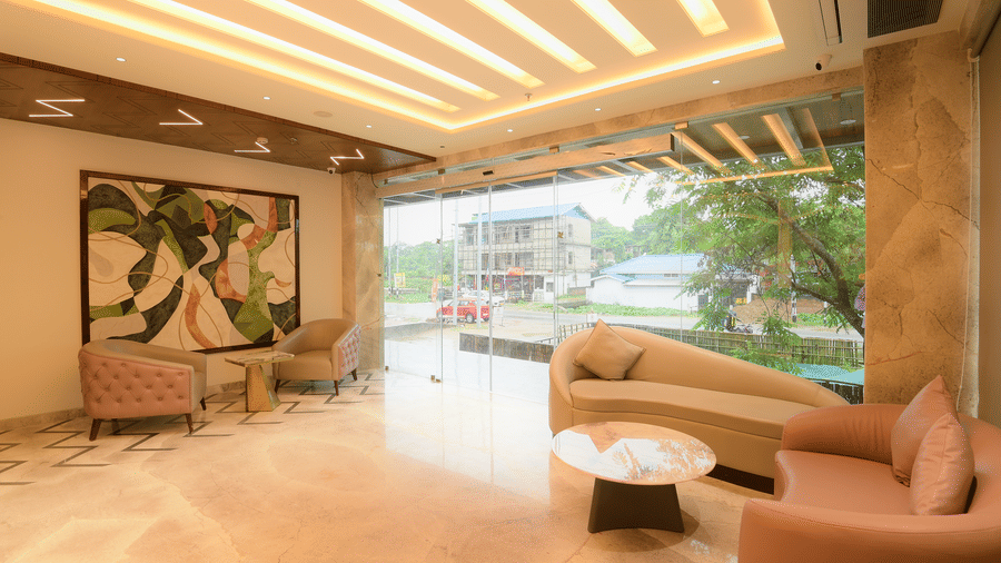 A lobby lounge offering comfortable plush sofas, a round coffee table, and a large glass window wall at Awesome Palace, Guwahati Airport.