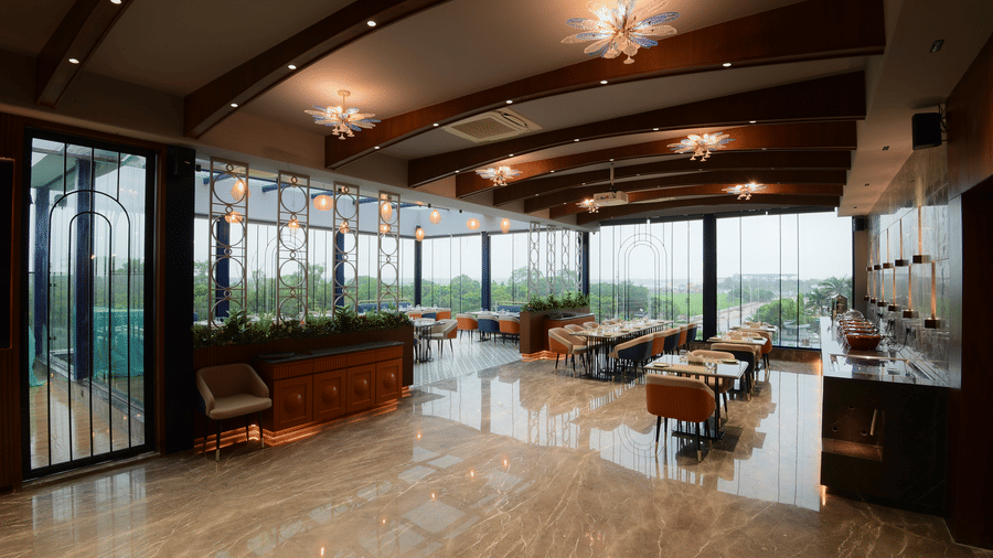 A view from the entrance showing a polished marble floor, dining tables with chairs, and decorative ceiling beams at Awesome Palace, Guwahati Airport.