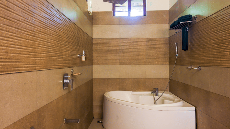 A modern bathroom at Ayur On The Beach Nattika featuring a tiled shower area and a curved corner bathtub.
