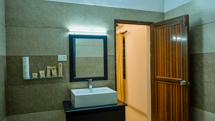 A bathroom vanity at Ayur On The Beach Nattika with a counter-top washbasin, mirror, and a laminated door.