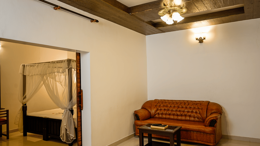 A comfortable living area at Ayur On The Beach Nattika featuring a sofa and a bedroom with a 4-poster canopy bed.