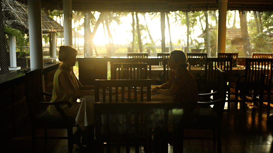 Two women sitting inside the restaurant with the sun setting in the background at Ayur On The Beach Nattika.