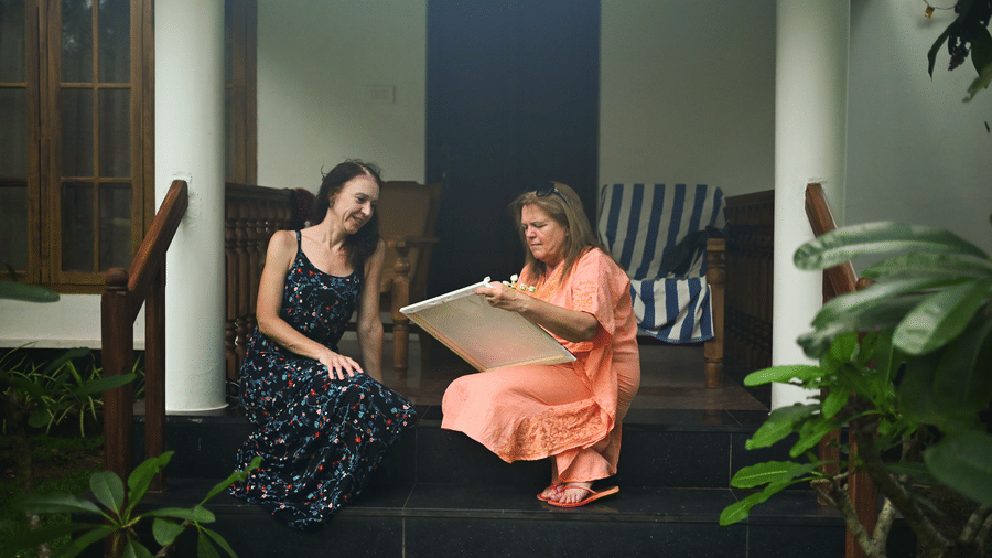 Two women sitting on the steps of the entrance to the villa at Ayur On The Beach Nattika.