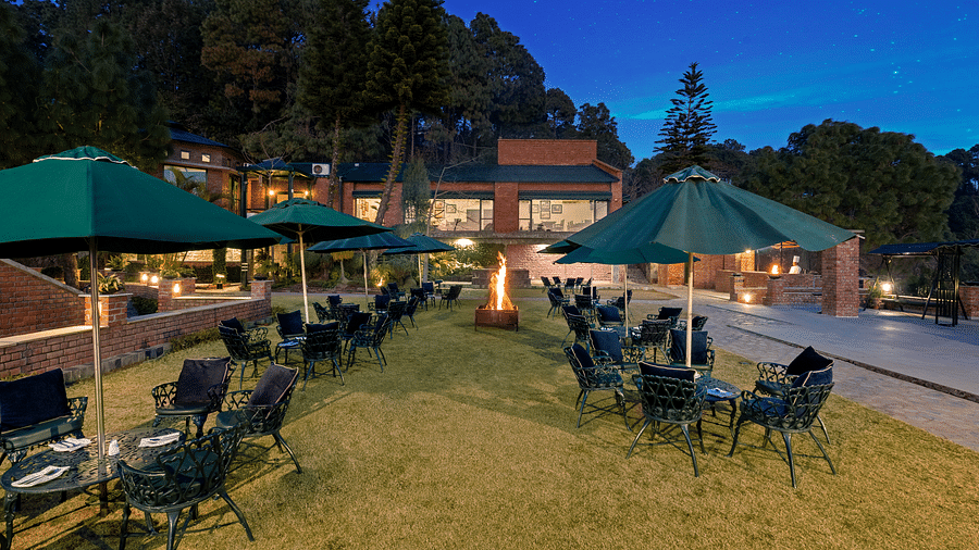 Outdoor Bonfire at Baikunth resort, kasauli with arranged chairs under the umberalla. 