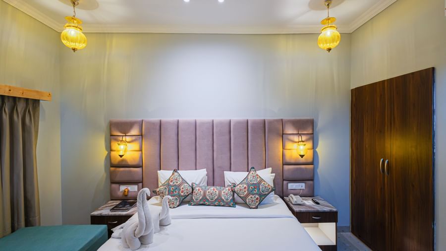 A close-up of a well-made bed with decorative cushions and a wooden headboard at Bamboo Saa Resort & Spa, Udaipur.