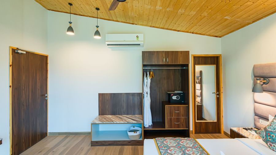 Sajjan Villa featuring a wardrobe, a bed, an AC, hanging lights from the ceilings, and a ceiling fan.