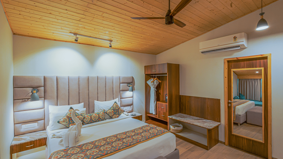 A bedroom featuring a double sized bed, a wardrobe, and a mirror attached on the door.