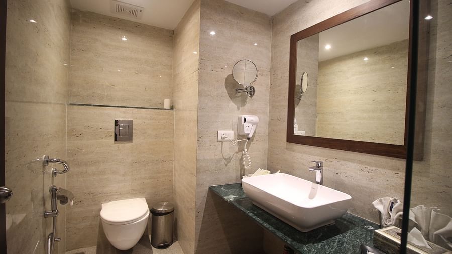 A clean, modern bathroom with a toilet, sink, and mirror. - Bamboo Saa Resort & Spa, Udaipur