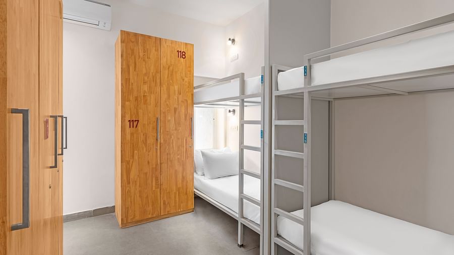 Dorms at Bedzzz in Varanasi feature a practical layout with built-in cupboards and a door, ensuring privacy and ample storage space. The design creates a comfortable environment for guests, making it an ideal choice for travelers seeking a cozy stay.