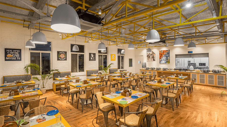 An image of a café interior featuring multiple tables set with menus and plates, chairs for dining, and the place is well lit.