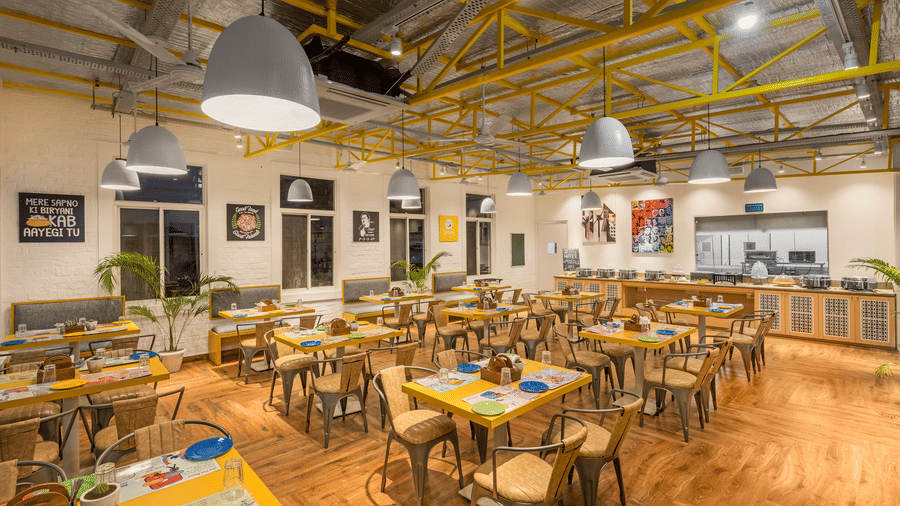 An image of a café interior featuring multiple tables set with menus and plates, chairs for dining, and the place is well lit.