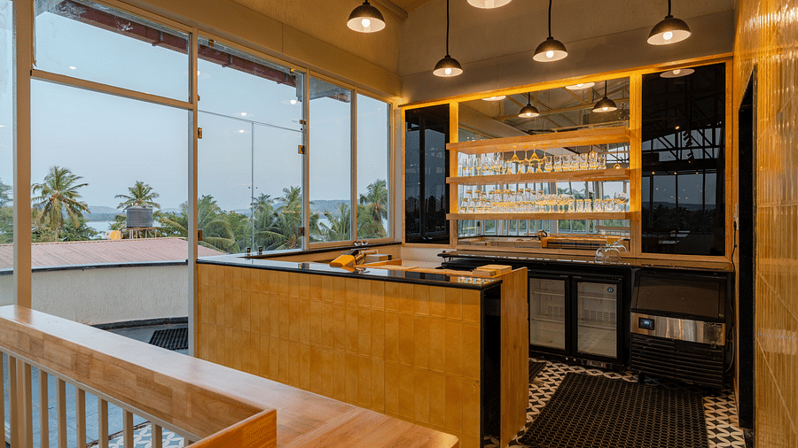 Interior of a contemporary cafe with bar stools and a window view. at Bedzzz Xclusiv Morjim, Goa