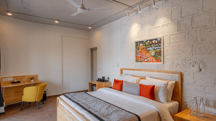 An image of hotel room with king size bed, painting on the wall, work desk and chair at one corner and a bedside table  at Bedzzz Xclusiv Morjim, Goa