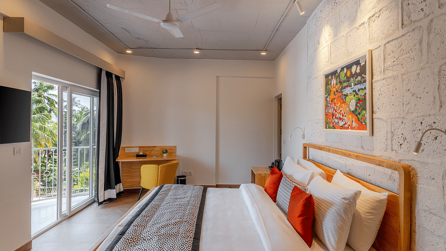 Bright hotel room with, flat TV screen, work desk and chair, vibrant art on the wall, and an access to the balcony at Bedzzz Xclusiv Morjim, Goa