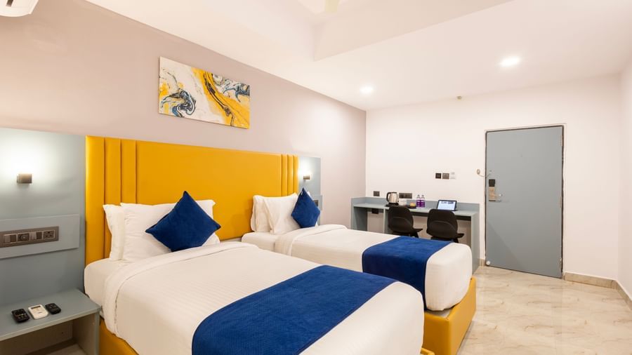 Full view of Superior Room featuring a bed with blue and white bedding, a yellow headboard, and modern furnishings including a desk and TV - Beestay Hotel Financial District, Hyderabad