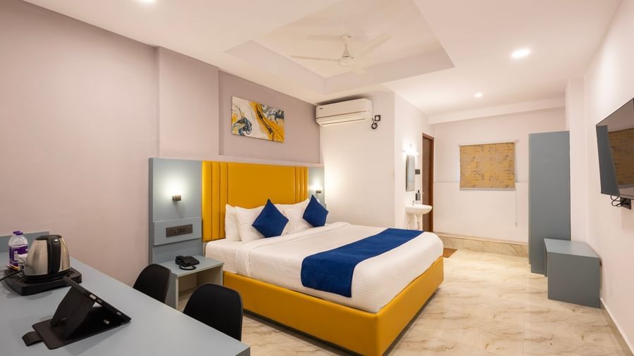 Full view of a modern Premium Room with a bed featuring blue accents, a work desk area, and a door on the left  - Beestay Hotels Financial District, Hyderabad 