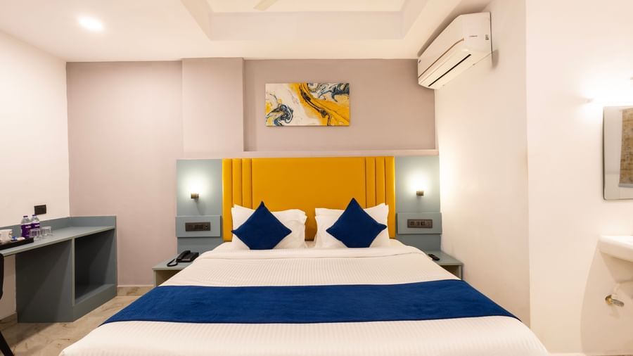 Close up of a modern Premium Room with a bed featuring blue accents, a work desk area, and a door on the left  - Beestay Hotels Financial District, Hyderabad 