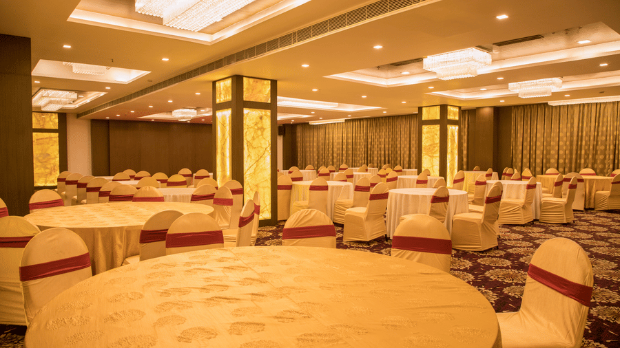 A large banquet hall at Benzz Park Chennai with multiple round tables and chairs, ready for a function.