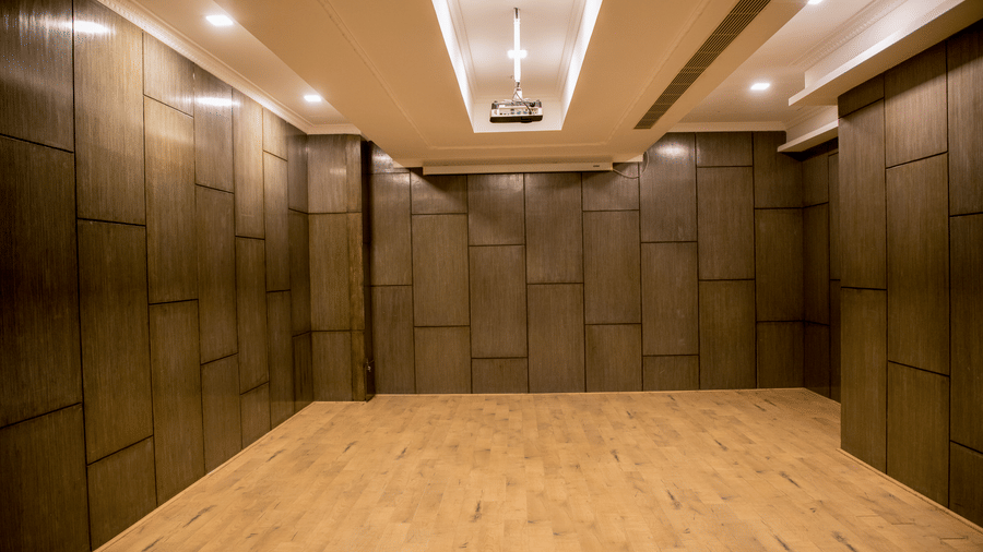 An empty, well-lit hall with light-coloured flooring and dark paneled walls at Benzz Park Chennai, suitable for various events.